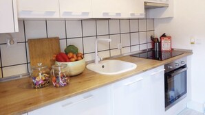 A kitchen with white cabinets, a wooden countertop, a sink, a stove, and a cutting board with vegetables. - BEAUTIFUL DESIGN FLOOR IN THE CENTER OF AVILA FOR 6 PEOPLE (Ávila)
