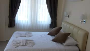 A hotel room with a bed, a bedside table, and a wall-mounted air conditioner.