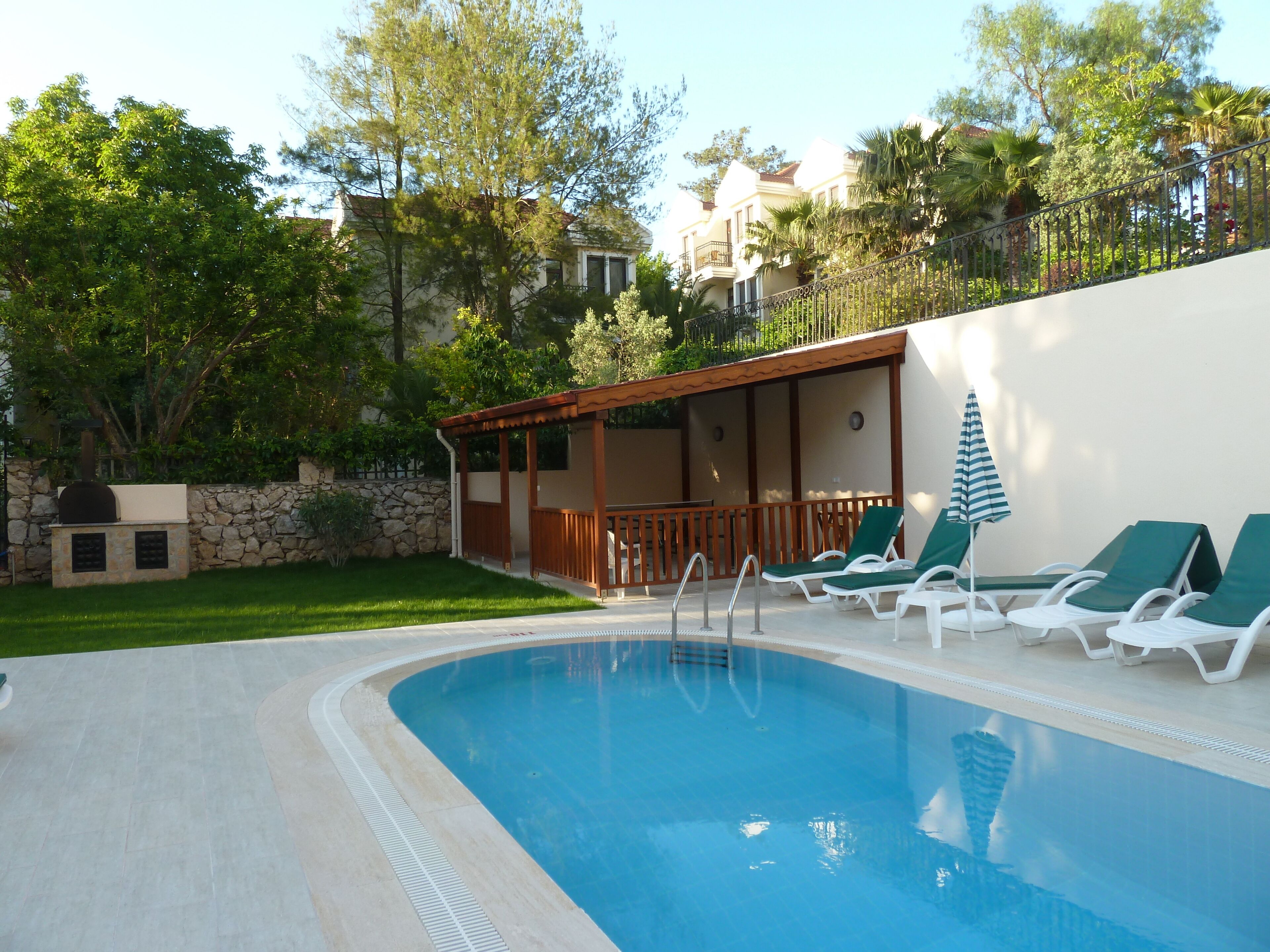 Ein Pool mit Liegestühlen und einer überdachten Sitzgelegenheit.