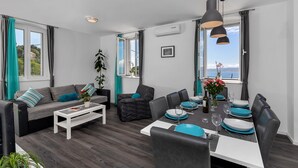 Una sala moderna con sofá, mesa de centro y mesa de comedor preparada para seis personas.