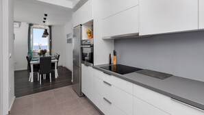 Una cocina moderna con armarios blancos, un refrigerador de acero inoxidable y un horno empotrado.