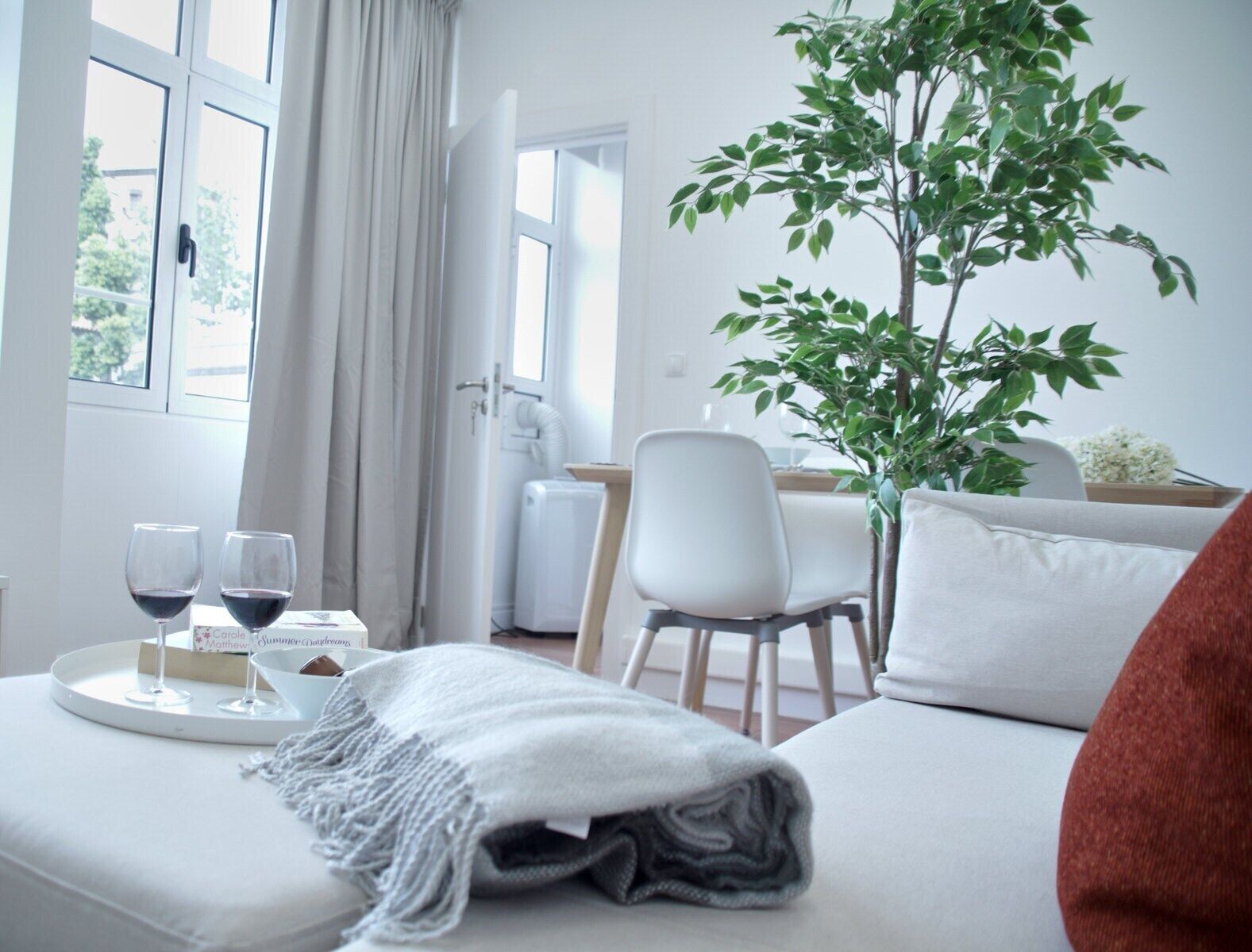 A cozy room with a bed, a dining table, and a potted plant.