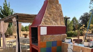 An outdoor kitchen with a stone chimney, a tiled backsplash, and a sink. - Cortijo rural bacares 1 (Freila)