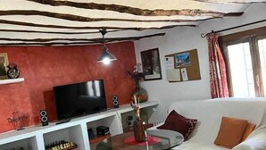A living room with a television, sofa, and a glass coffee table. - Cortijo rural bacares 1 (Freila)