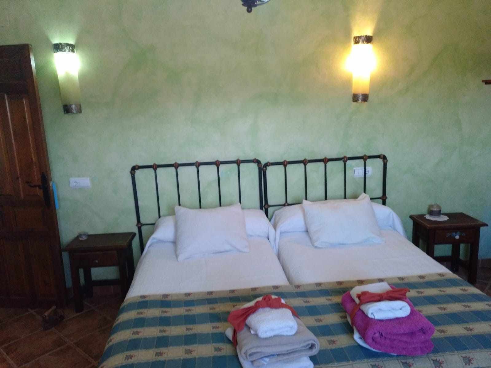 Una cama doble con dos almohadas, una colcha a cuadros y dos mesitas de noche con lámparas.