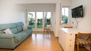 Una sala de estar con un sofá, una mesa de comedor y un televisor montado en la pared.