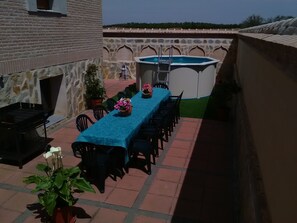 Un patio al aire libre con una mesa larga, sillas, una parrilla y un jacuzzi.