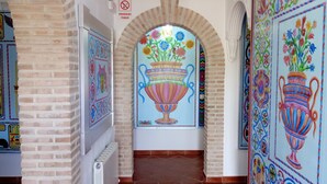 A hallway with a tiled floor, brick walls, and colorful murals on the walls.