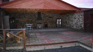 Un edificio de piedra con techo rojo, chimenea y asientos al aire libre.