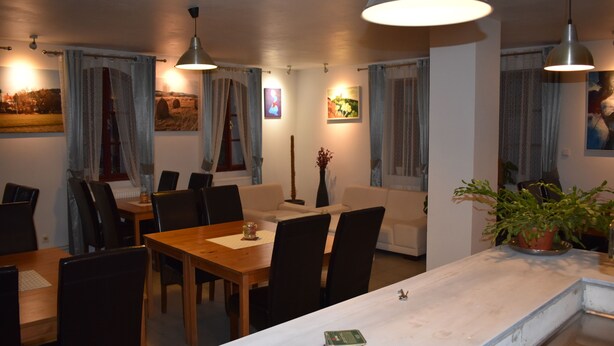 Un comedor con mesa y sillas de madera, un sofá blanco e iluminación colgante.