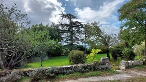 Un muro di pietra con un'area verde e alberi.