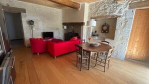 Un accogliente soggiorno con un divano rosso, un tavolo da pranzo in legno e una parete in pietra.