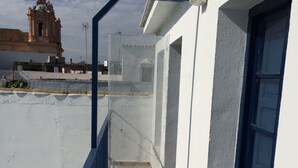 A balcony with a metal railing, a white wall, and a blue door. - Commander's corner (Tocina)