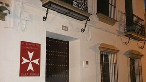 A building with a dark entrance door, a balcony with wrought iron railings, and a sign with a star and text. - Commander's corner (Tocina)