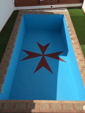 A rectangular swimming pool with a blue interior and a red star design in the center.
