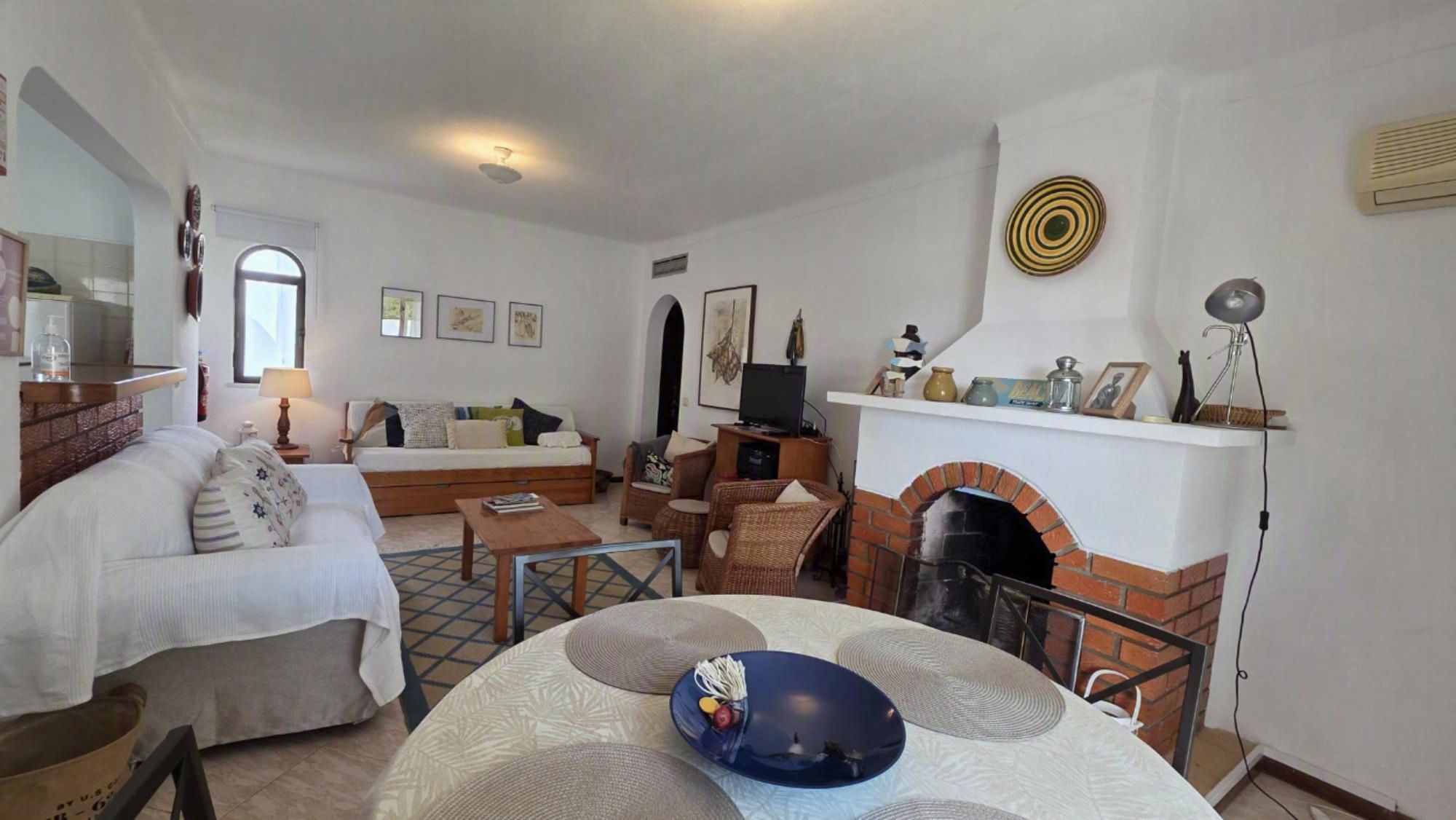 A living room with a fireplace, a sofa, a coffee table, and a dining table.
