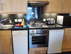 Enjoy cooking in this well-equipped kitchen with a range hood, dishwasher, compact oven, sink, toaster, and microwave.