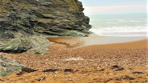 A rocky beach with a cliff and ocean view.