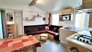 A compact living space with a kitchenette, a sofa, a dining table, and a microwave.
