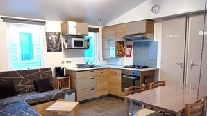 A compact kitchen with a microwave, stove, and oven. There is a dining table with chairs and a sofa with a coffee table.