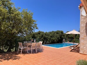 A pool area with a table and chairs, surrounded by a stone wall and a metal fence. - Secluded Villa Antikleia with private pool (Fiskardo)