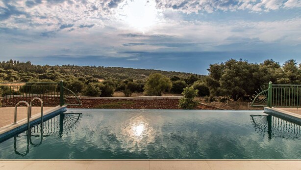 Une piscine offrant une vue sur un paysage vallonné et des arbres.