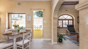 A dining area with a table set for four, a chair, and a potted plant. - Holiday home in Gozo with private pool, quiet location & family friendly  (Gharb)