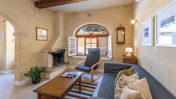 A cozy living room with a fireplace, comfortable seating, and a stone wall. - Holiday home in Gozo with private pool, quiet location & family friendly  (Gharb)
