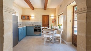 A kitchen with blue cabinets, a wooden ceiling, and a dining area with white chairs. - Holiday home in Gozo with private pool, quiet location & family friendly  (Gharb)