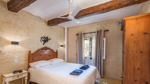 A bedroom with a wooden bed, a nightstand, a ceiling fan, and a wardrobe. - Holiday home in Gozo with private pool, quiet location & family friendly  (Gharb)