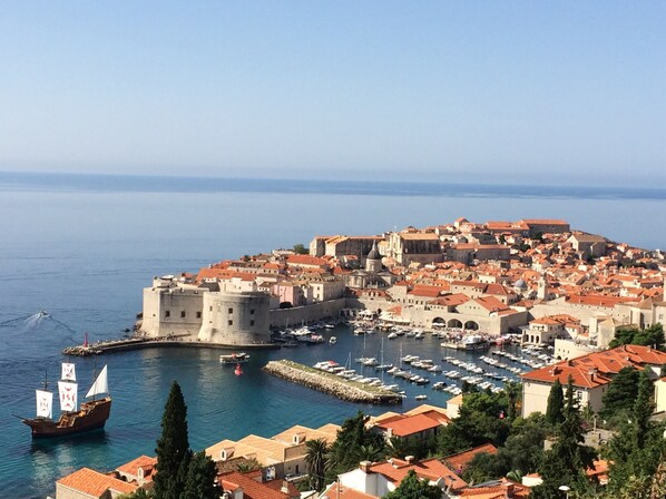 Une ville côtière dotée d’une architecture historique, d’un port où sont amarrés des bateaux et d’un imposant édifice qui ressemble à un château.