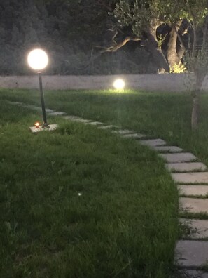 A nighttime outdoor area with a pathway and two illuminated light posts.