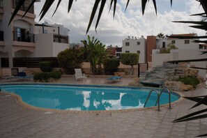 A swimming pool with lounge chairs and a rock feature.