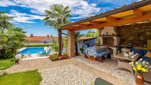 Un patio con piscina, mobiliario exterior y un muro de piedra.