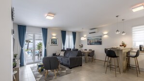 Een moderne woonkamer met een bank, eettafel en een barretje.