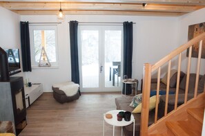 A cozy living room with a wooden floor, a sofa, a small table with drinks, and a staircase.