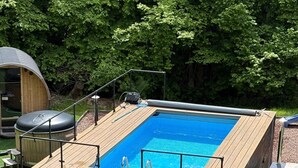 Piscina retangular com deck de madeira e guarda-corpo de metal.