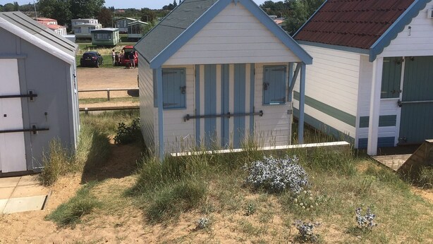Ein kleines Strandhaus mit geneigtem Dach und einem Fenster.