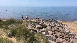 Ein felsiger Strand mit Menschen in der Nähe des Wassers.