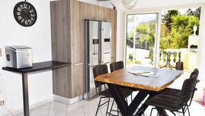 Una cocina moderna con una mesa y sillas de madera, un refrigerador de acero inoxidable y un reloj en la pared.
