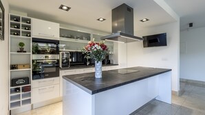 Une cuisine moderne avec des meubles blancs, un îlot central et un four encastré.