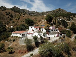 Stunning hillside property with Mediterranean architecture, surrounded by lush vegetation and rugged terrain.
