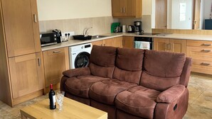 Une cuisine moderne avec des meubles en bois, un canapé, une table et un lave-linge.