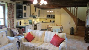 Un salón acogedor con sofá, una mesa de comedor y una zona de cocina con microondas y armarios.