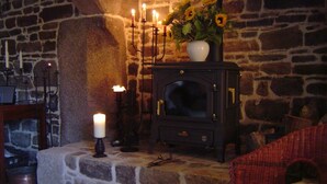 Una chimenea de piedra con un jarrón de girasoles, velas encendidas y una silla de mimbre roja.