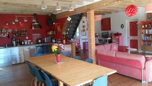 Eine gemütliche Küche mit modernen Geräten, ein Essbereich mit Holztisch und -stühlen sowie ein Wohnbereich mit Sofa und Fernseher.