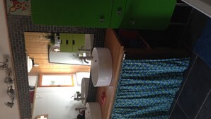 Ein Badezimmer mit einem grünen Schrank, einem weißen Waschbecken und einem duschvorhang mit Muster.
