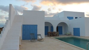 A white building with blue doors and a swimming pool.