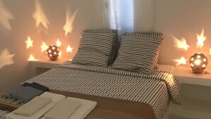 A bedroom with a bed, pillows, a bedside table, and a nightstand.
