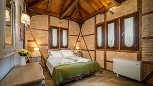 A bedroom with a wooden ceiling, brick walls, a bed with a green bedspread, a nightstand with a lamp, and a radiator. - Fairytale Villa, in the heart of Lefkas town and Agios Ioannis beach! (Lefkada)
